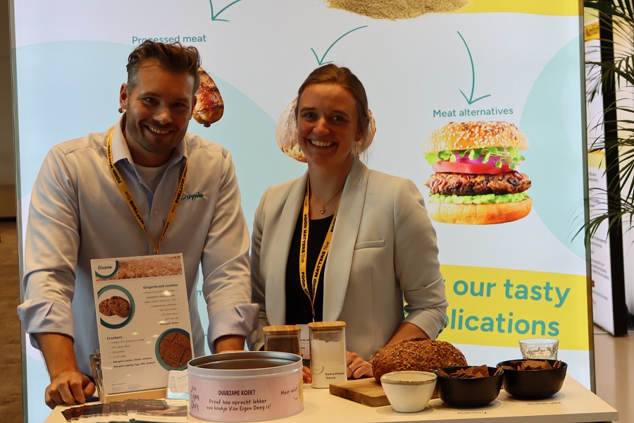 a man and a woman at a trade show booth with food samples